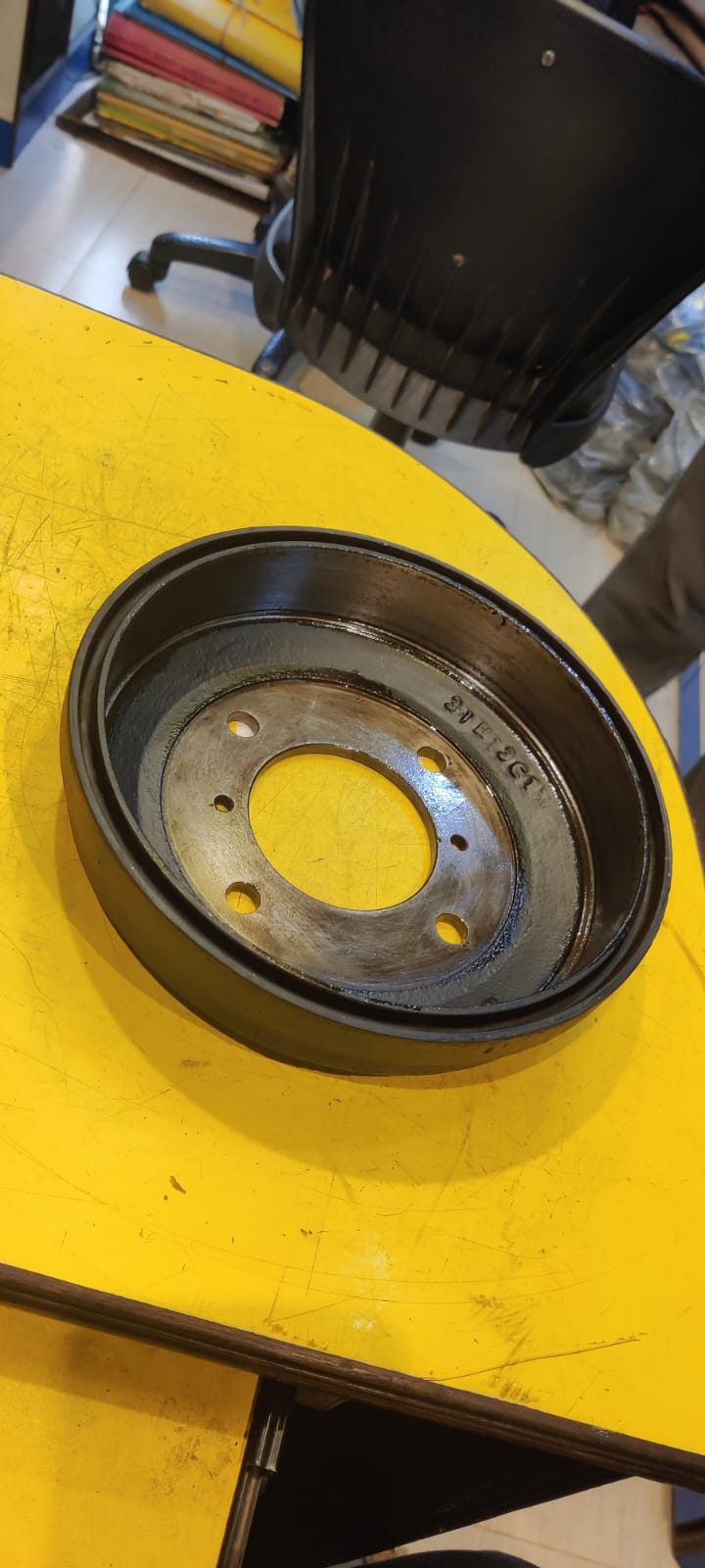 Metal brake drum on a yellow surface with a blurred background