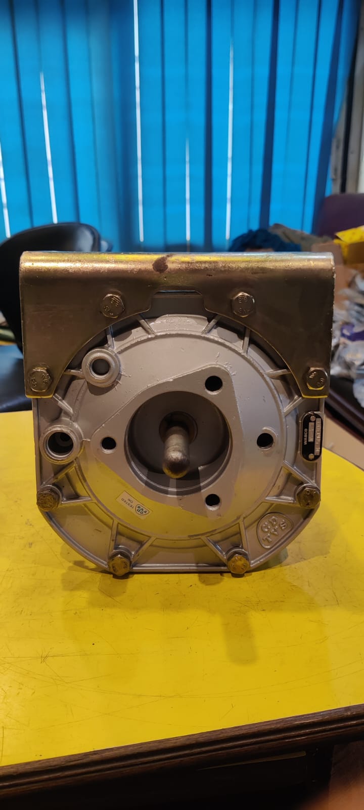 Mechanical component on a yellow surface with a blue curtain background