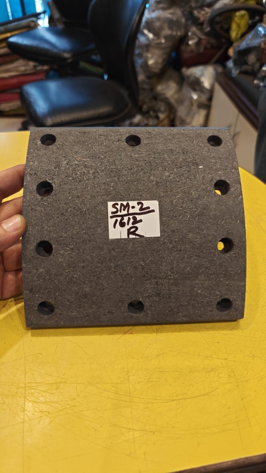 Black rubber block with measurement markings held by a hand on a yellow surface