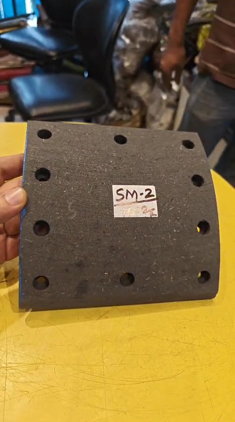 Black rubber block with multiple holes and a label on a yellow surface