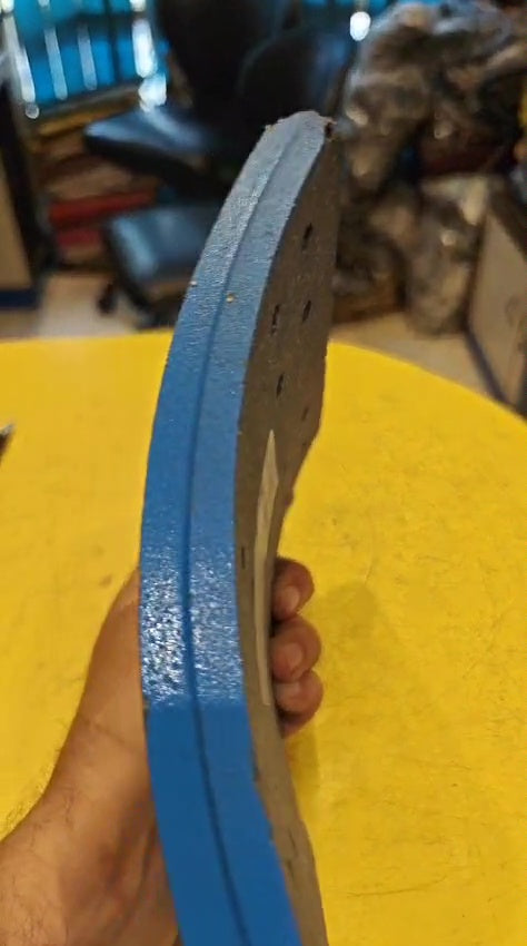 Close-up of a blue sanding belt held by a hand on a yellow surface.