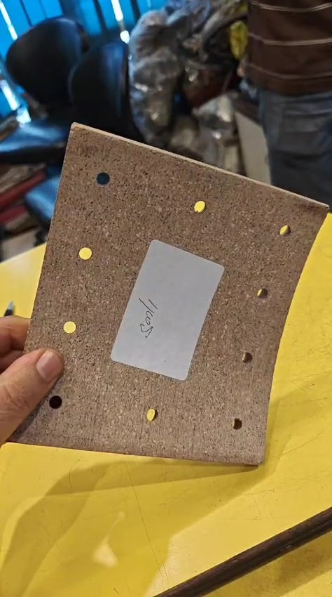 Brown cardboard with gold studs and a card on a yellow surface