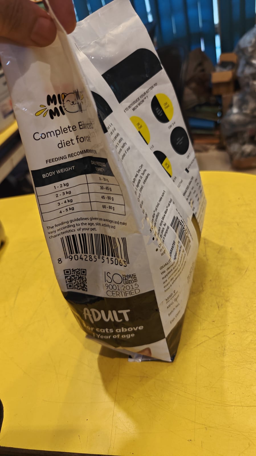 Pet food packaging with visible branding on a yellow surface