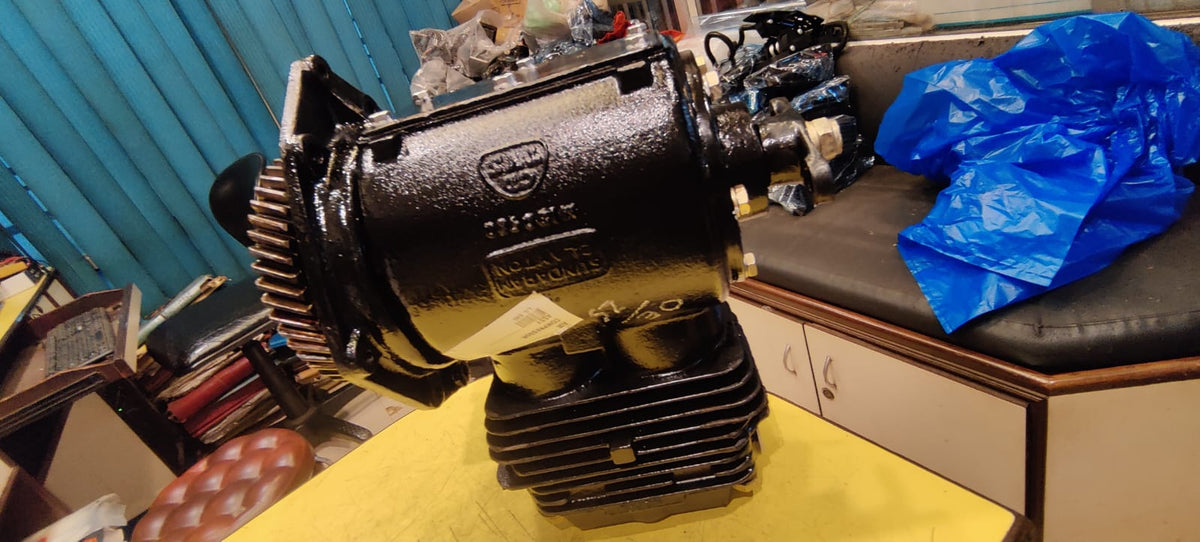 Large black mechanical component on a yellow surface with blue plastic bags in the background.