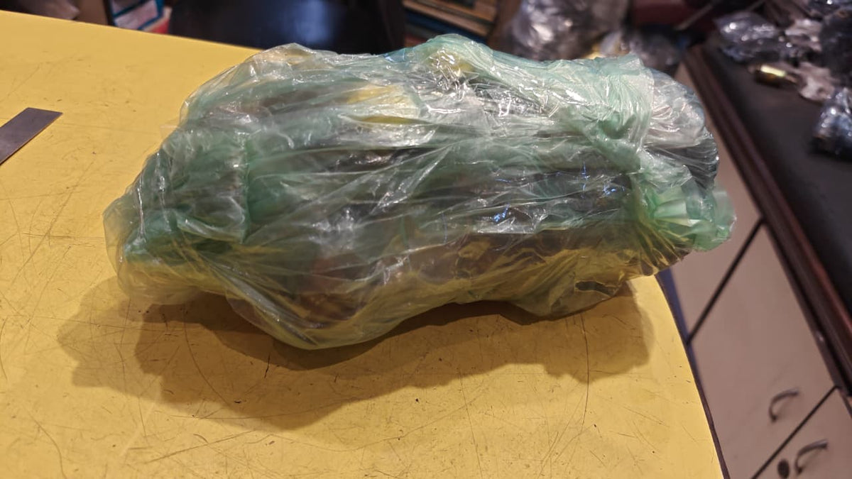 Green leafy vegetable wrapped in plastic on a yellow surface