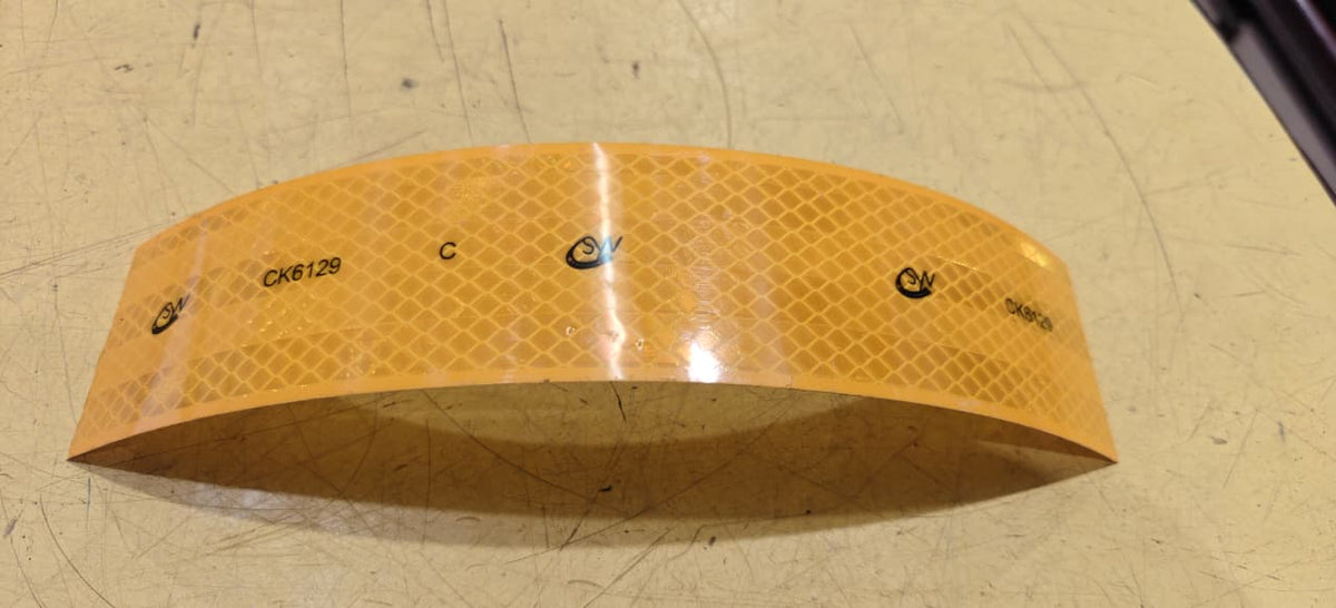 Yellow Reflective tape with brand logo on a textured surface