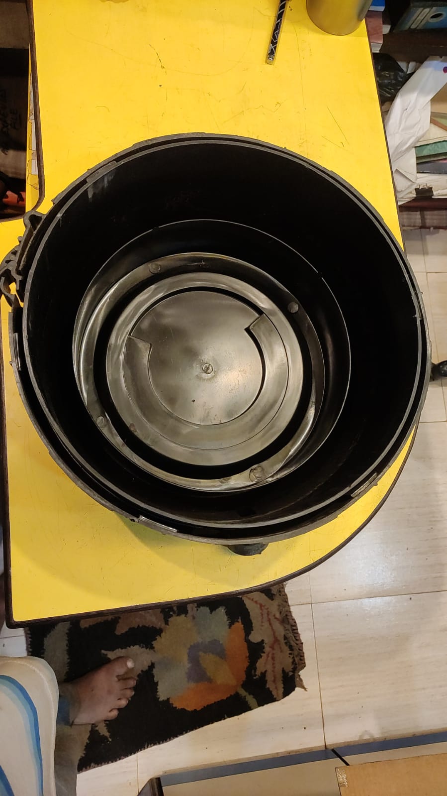 Black metal container on a yellow surface with a blurred background