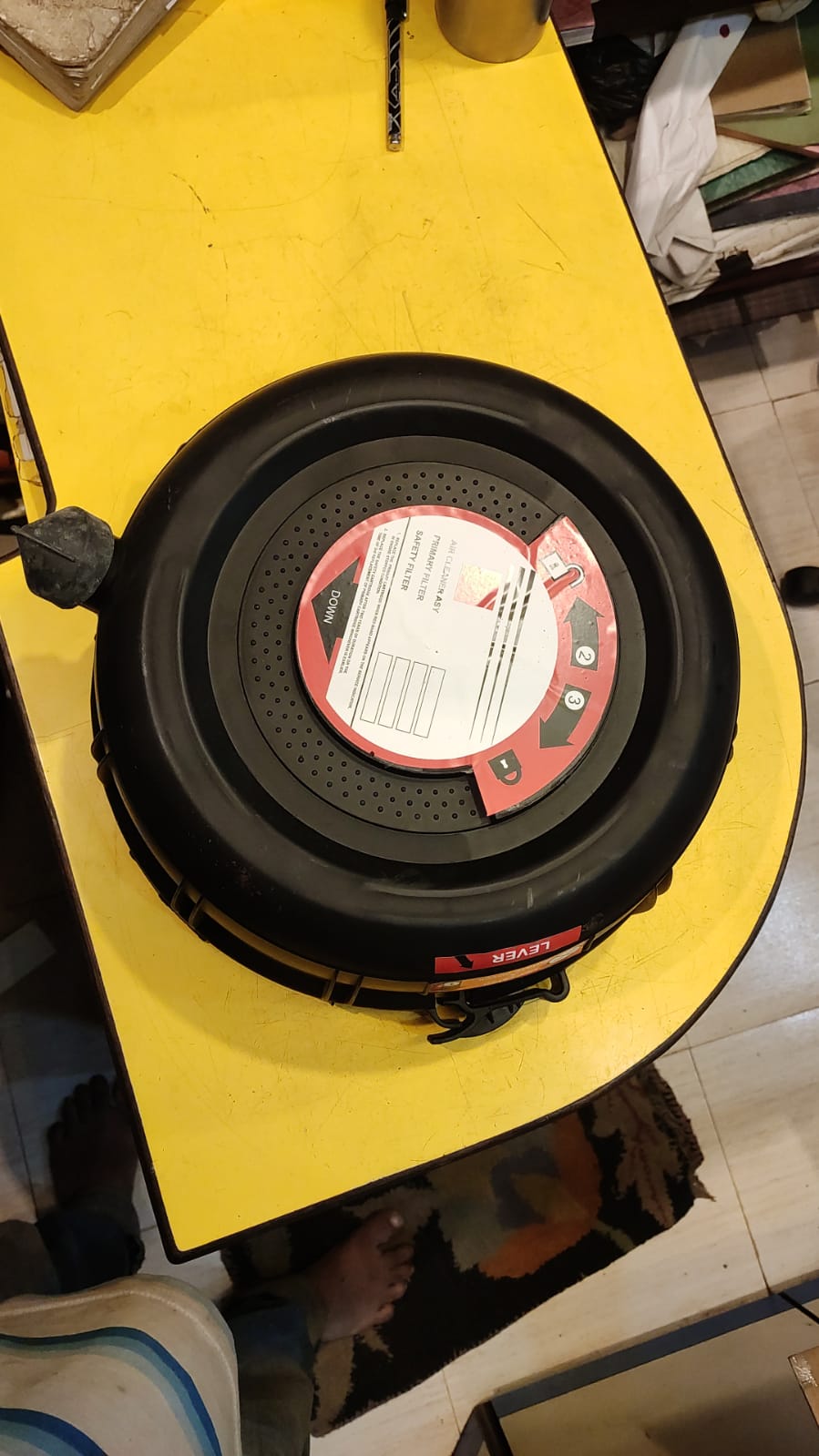 Black speaker on a yellow surface with a visible brand label.