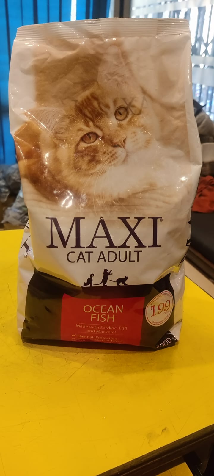 Bag of Maxi Cat Adult Ocean Fish cat food on a yellow surface