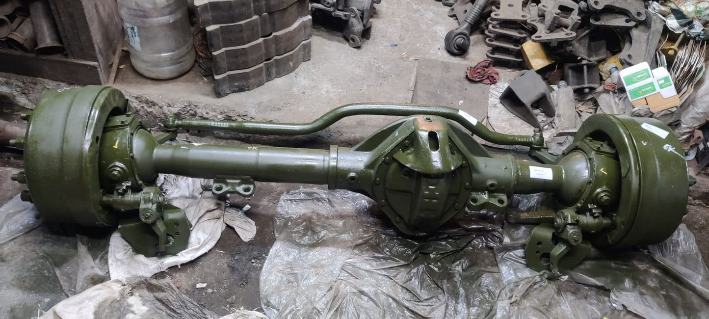 Automotive axle assembly on a workshop floor with tools and equipment in the background