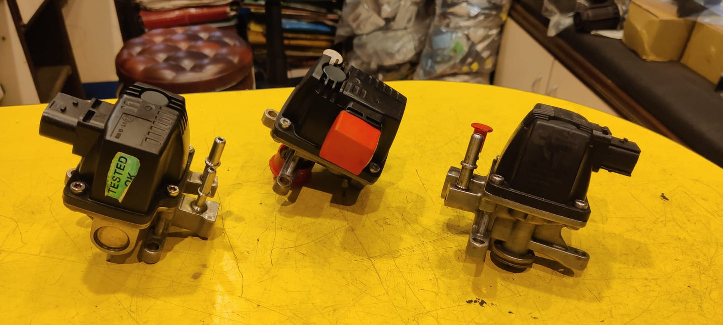 Three mechanical components on a yellow surface with a blurred background