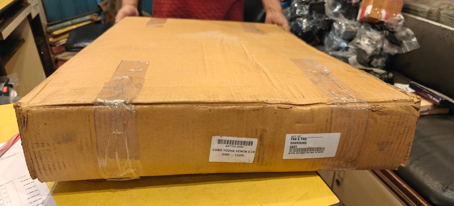 Large cardboard box with shipping labels held by a person in an indoor setting.