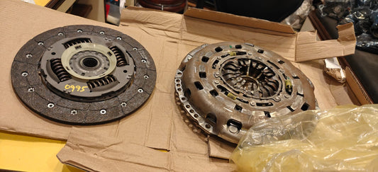 Two clutch discs on a cardboard surface with a plastic bag partially covering them.