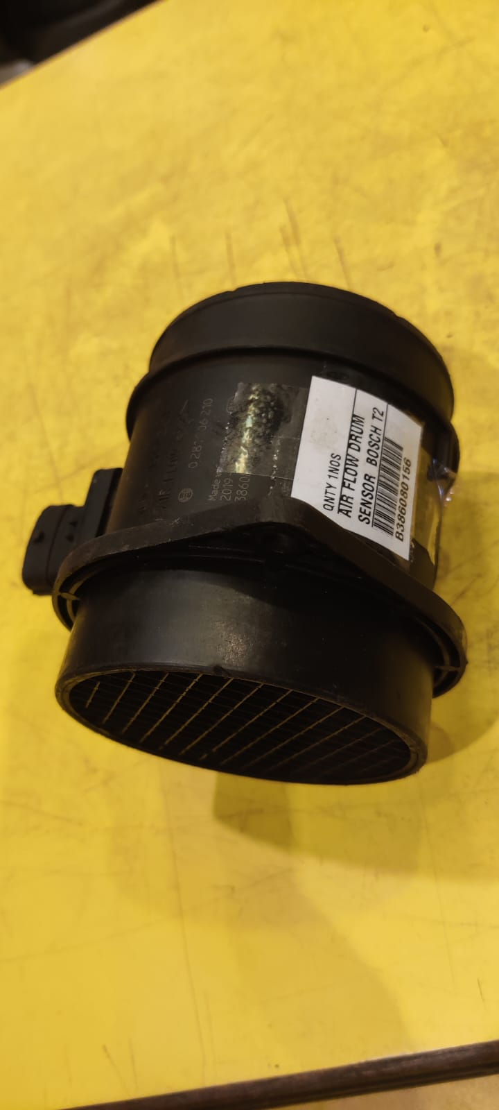 Black automotive part with a label on a yellow background