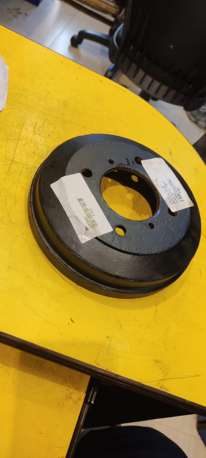Black brake drum with labels on a yellow surface