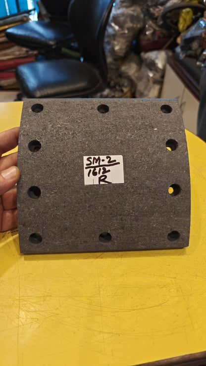 Black rubber block with measurement markings held by a hand on a yellow surface