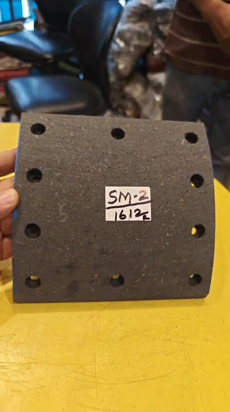 Black square object with holes and a label on a yellow surface