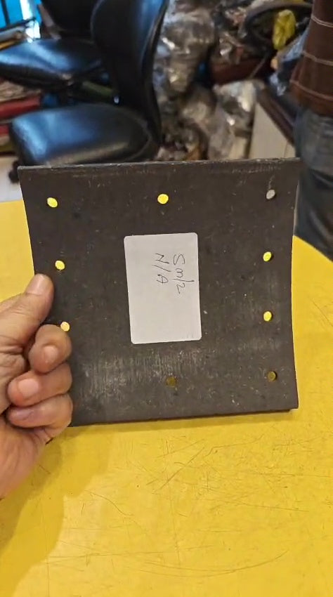 Hand holding a black rectangular object with a label on a yellow surface