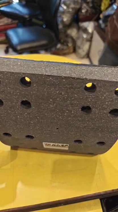 Black metal bracket with holes on a yellow surface