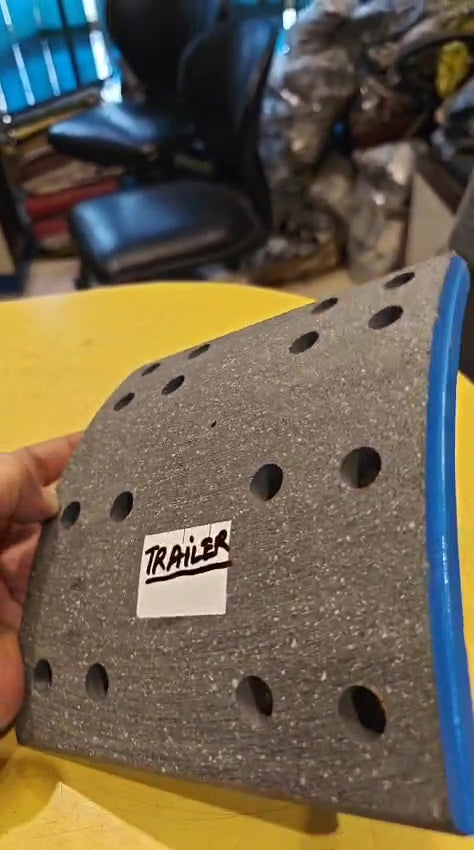 Gray textured object with a 'Trailer' label held by a hand on a yellow surface.