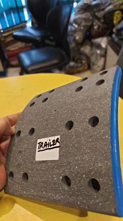 Gray textured object with a 'Trailer' label held by a hand on a yellow surface.