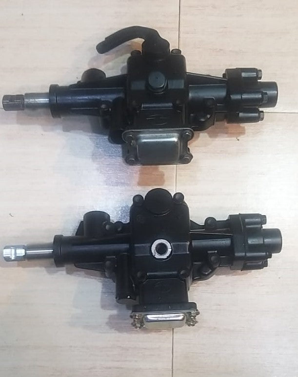 Two black mechanical components on a light wooden surface