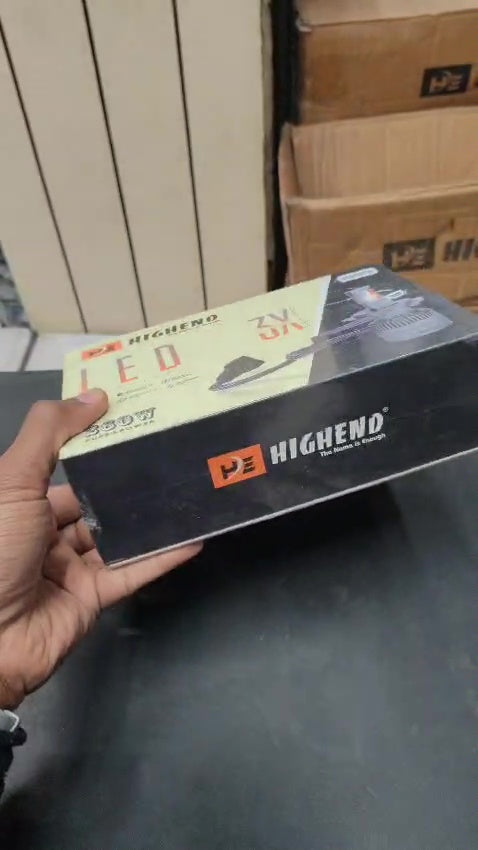 Hand holding a 'HIGHEND' LED light box with stacked boxes in the background.