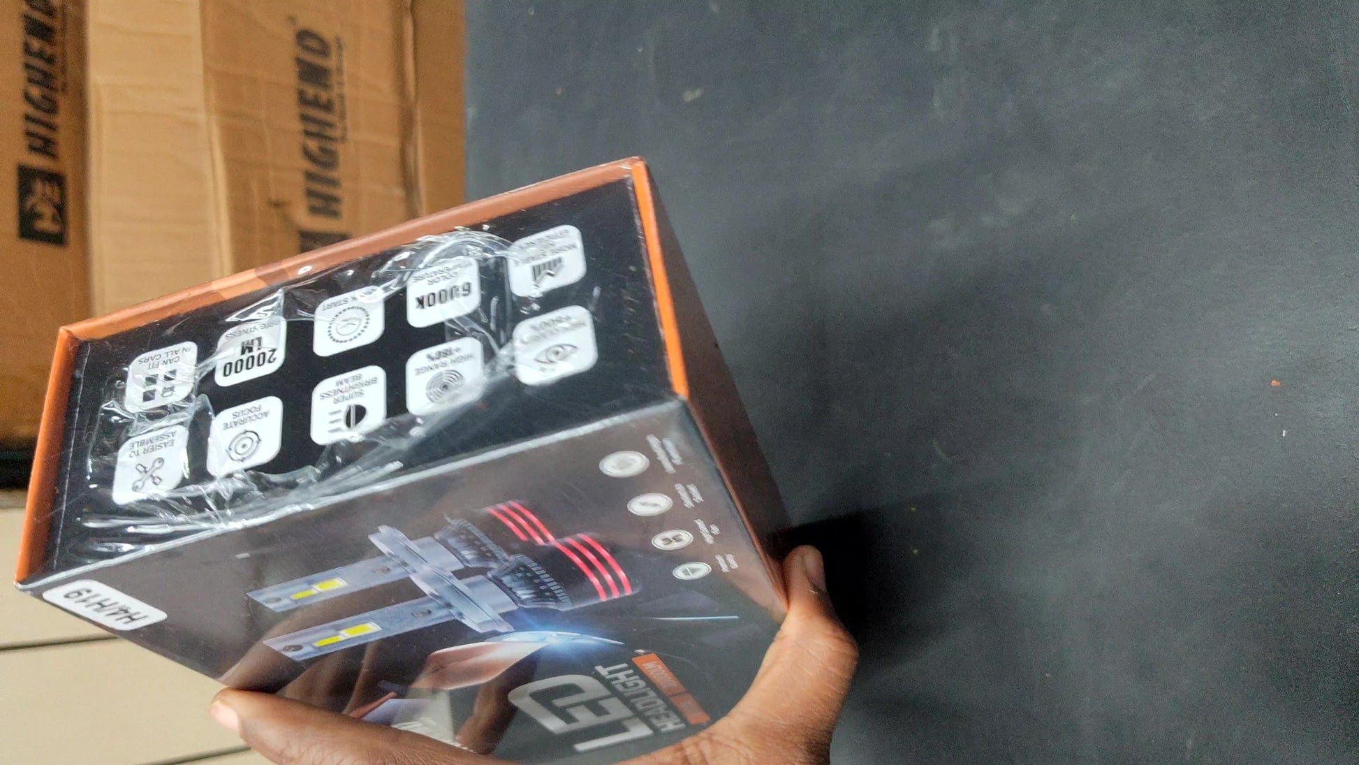 Hand holding a box with technical graphics on a dark surface