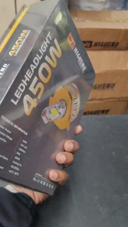 Hand holding a LED headlight box with '450W' on a blurred background