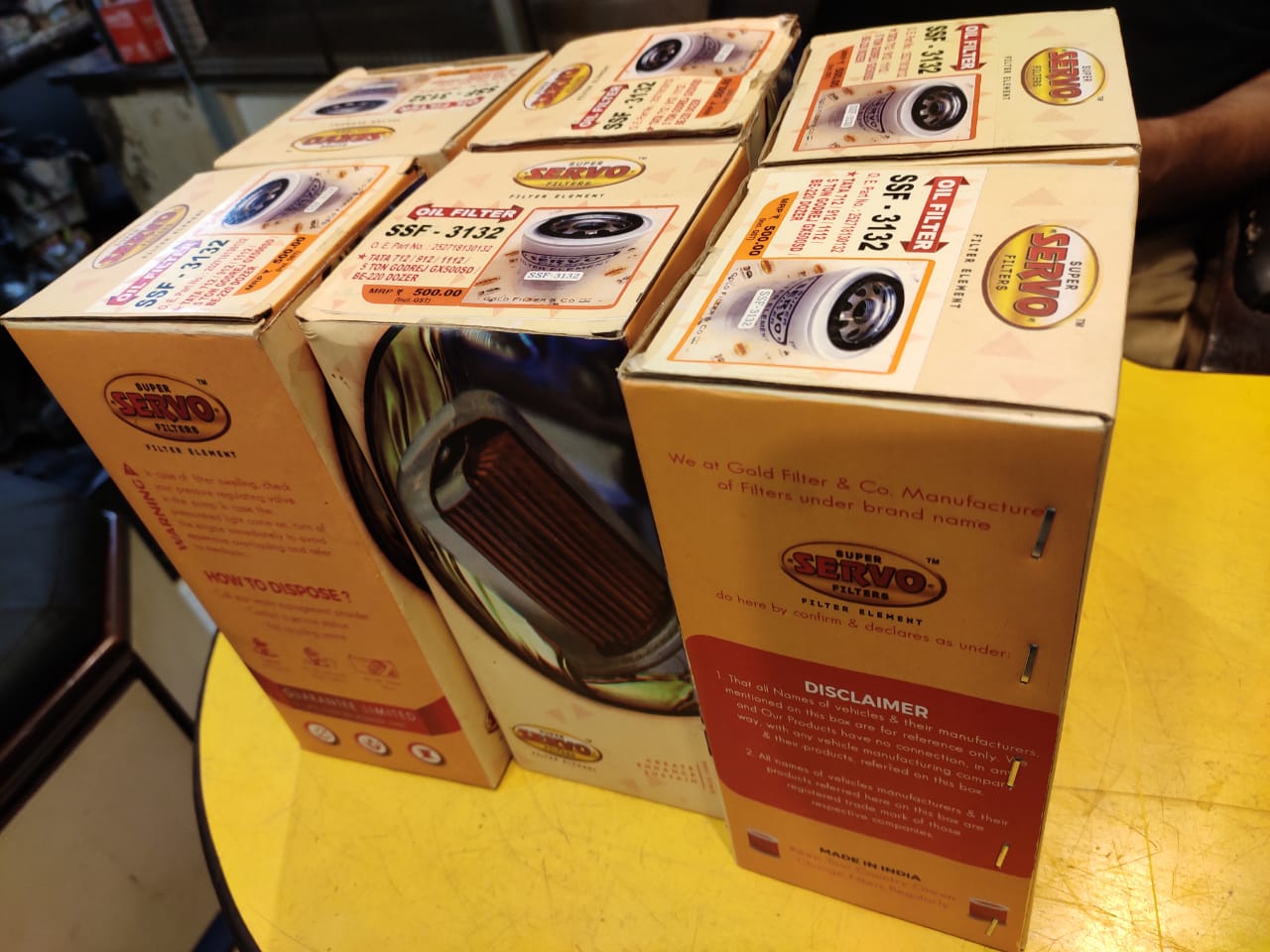 Stack of Sero oil boxes on a yellow surface with a blurred background