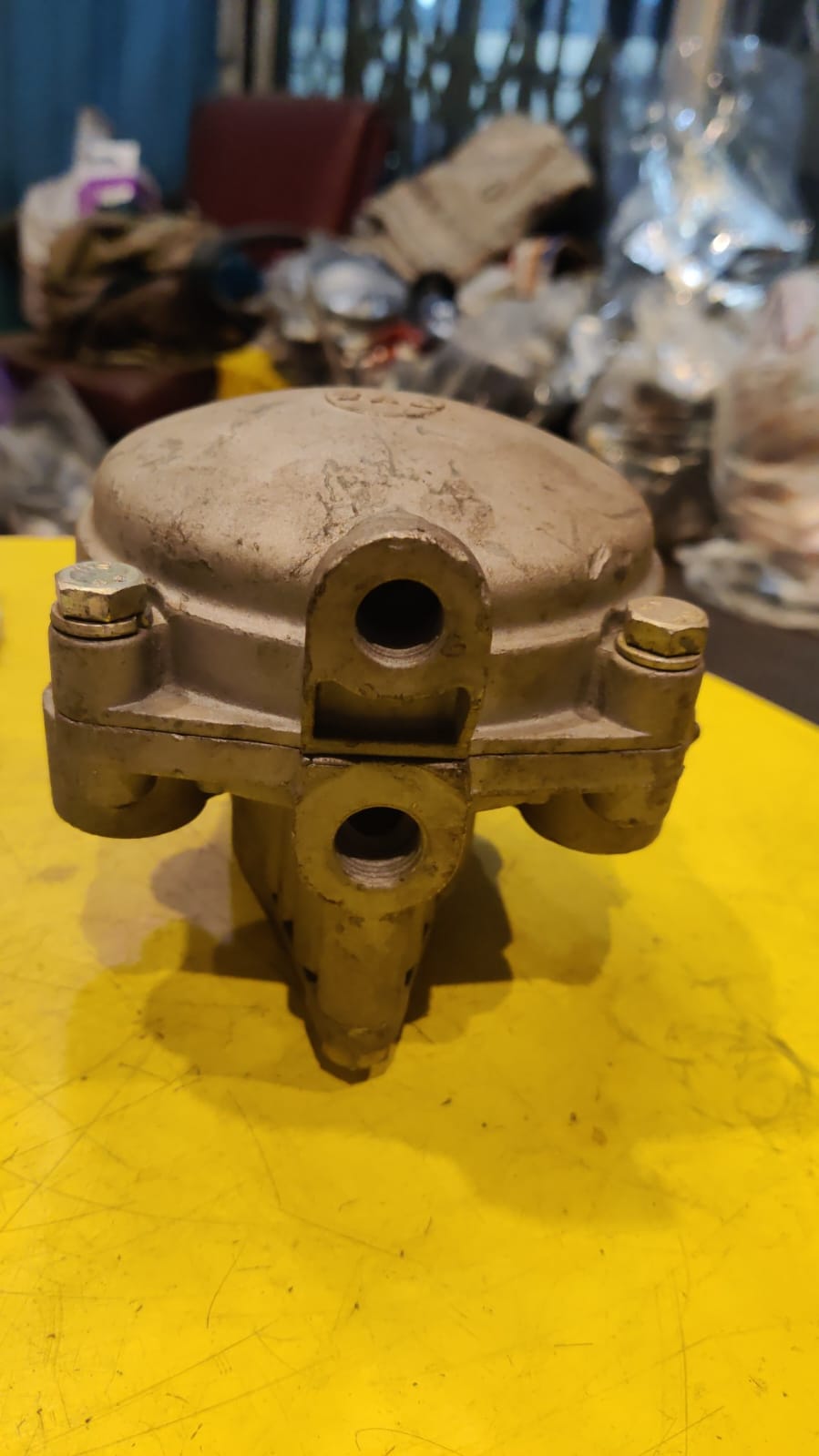 Metal mechanical component on a yellow surface with a cluttered background