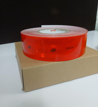 Red reflective tape on a cardboard box with a dark background