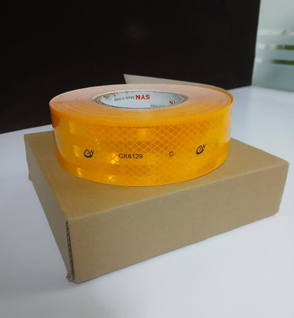 Roll of yellow reflective tape on a cardboard box with a dark background