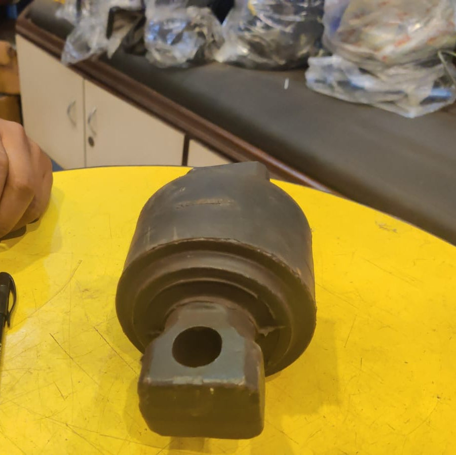 Two mechanical components on a yellow surface with a person's hand in the background.