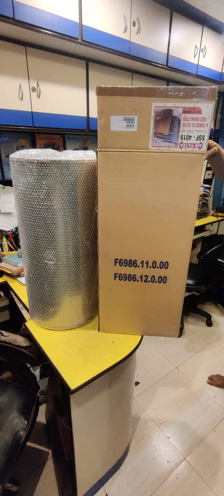 Cardboard box with a roll of wire mesh on a yellow table in an office setting.