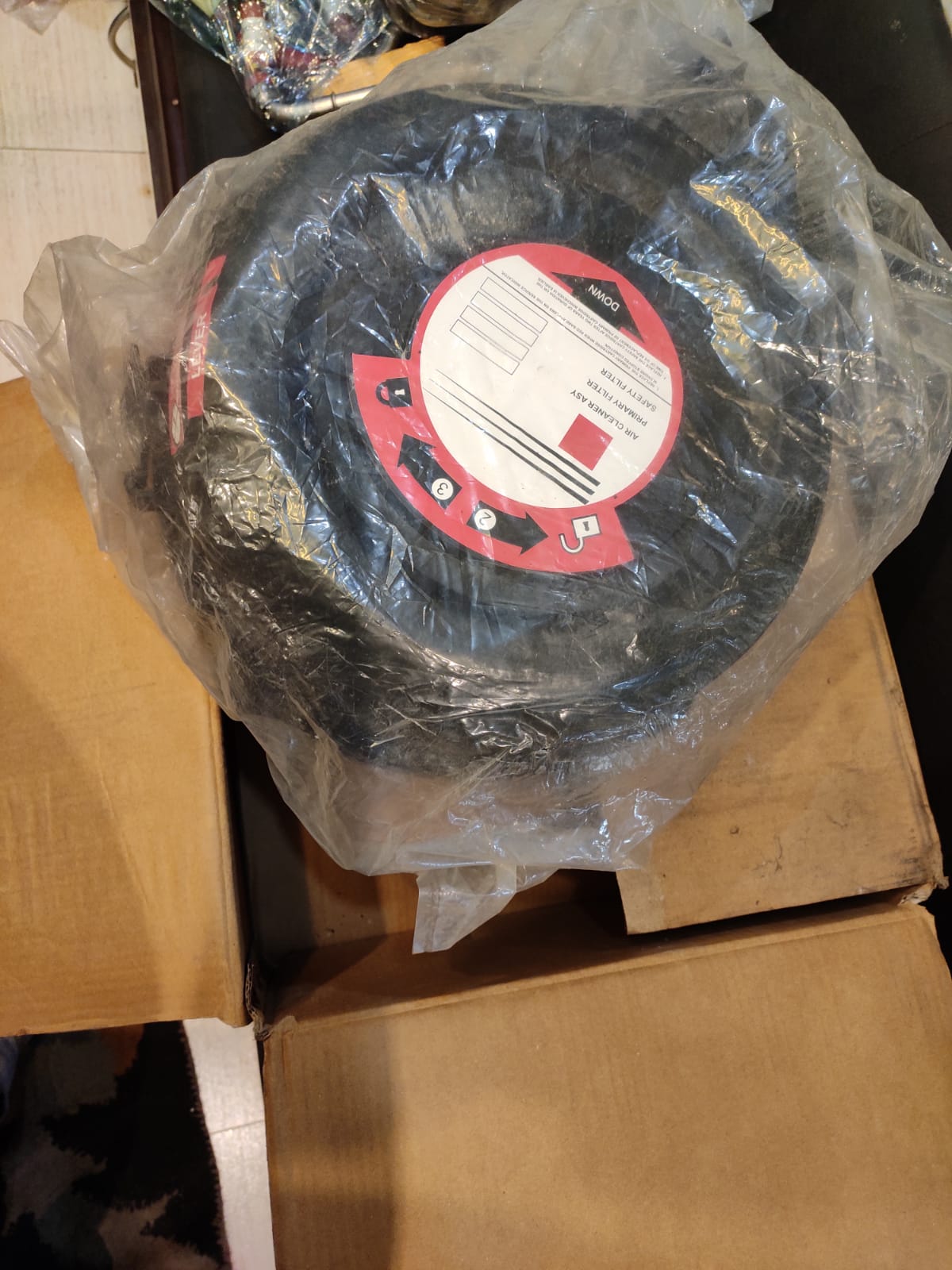 Black circular object with a red label on a cardboard surface