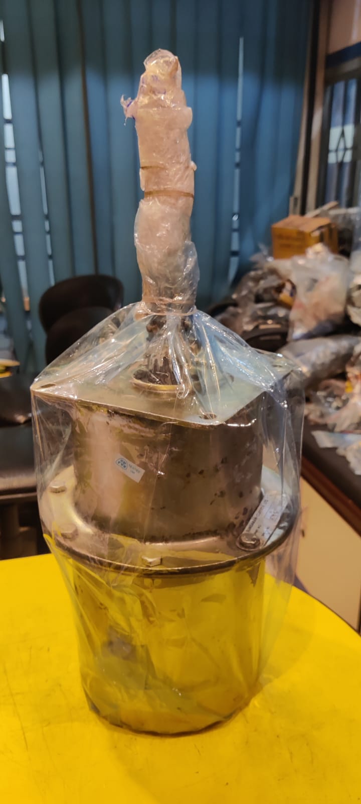 Clear plastic bag with a cylindrical object inside on a yellow surface.