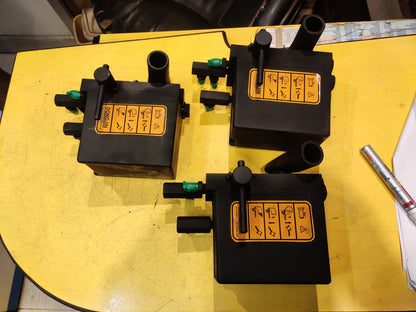Three black mechanical devices with yellow labels on a yellow surface.
