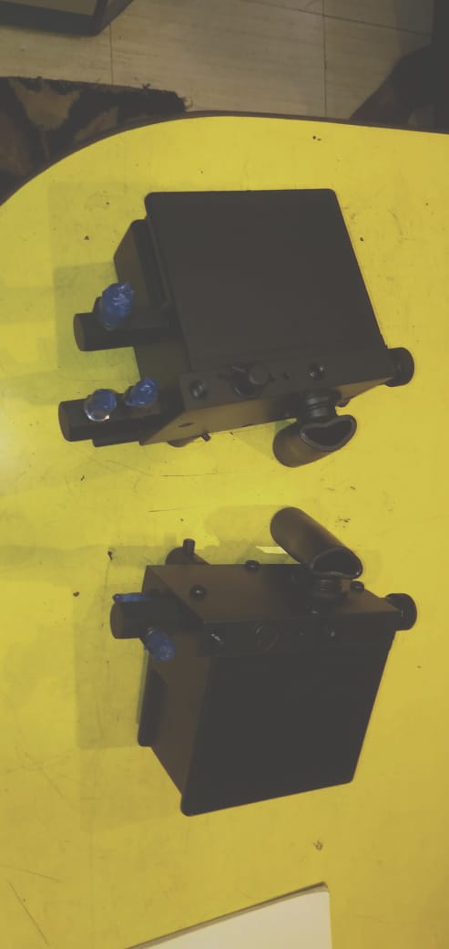 Two black mechanical components on a yellow surface