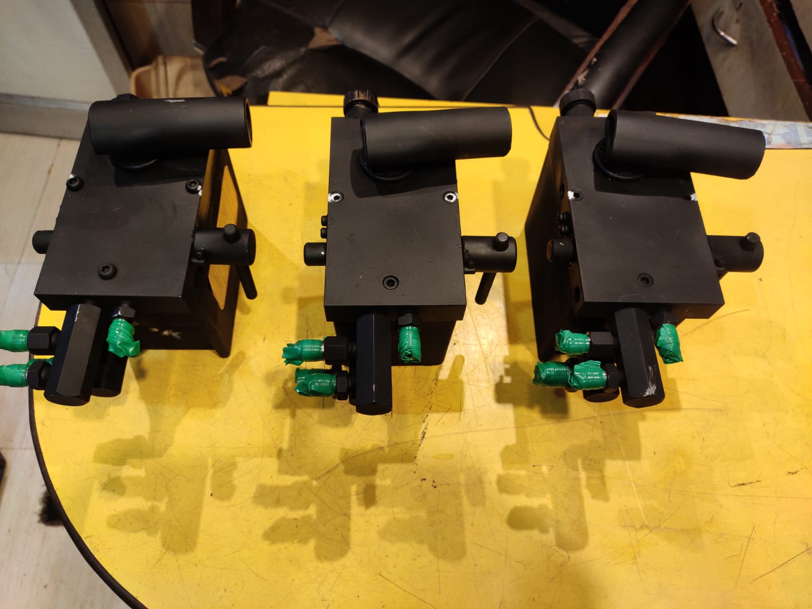 Three black mechanical components on a yellow surface