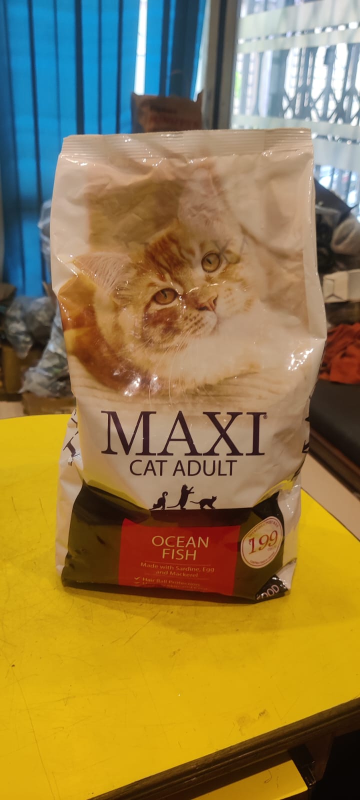 Bag of Maxi Cat Adult Ocean Fish cat food on a yellow surface
