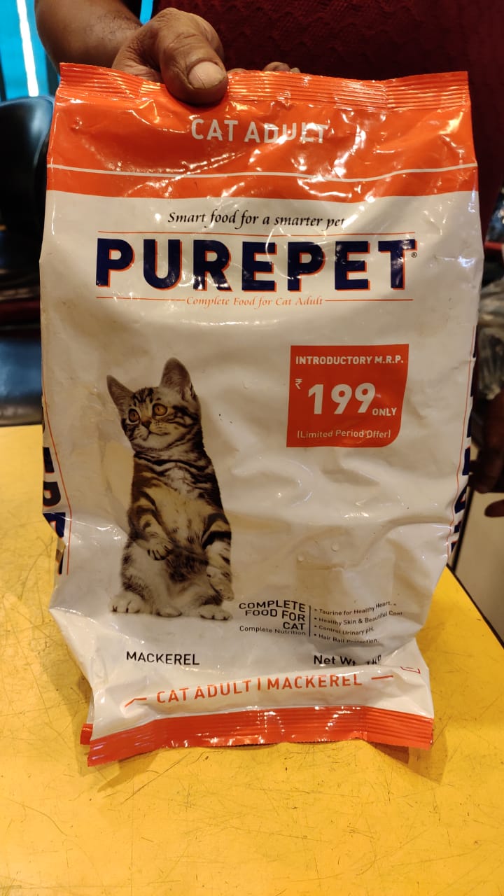 Bag of Purepet cat food with a cat on the label, held by a person.