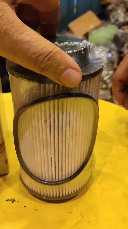 Hand holding a cylindrical filter on a yellow surface with a blurred background